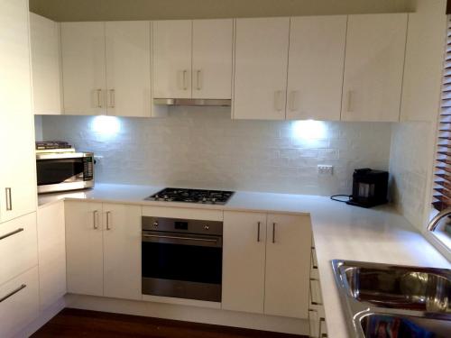 A kitchen with white storage spaces, white counter top, and a gas stove with oven.