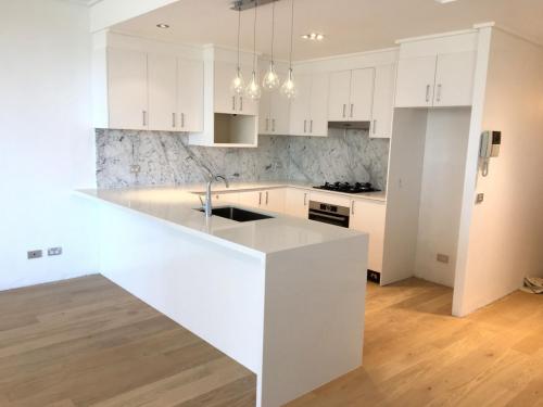White kitchen renovated from scratch contrasting on timber flooring.